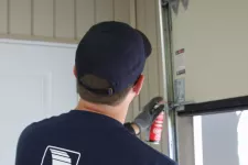 Un technicien certifié en train de lubrifier les roulettes d'une porte de garage